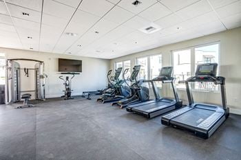 High end fitness center with cardio equipment, weights, and stretching area